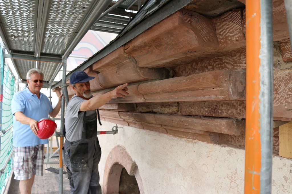 Der Zahn der Zeit hat am Kirchturm von St. Michael genagt – Polier Berthold Bartel zeigt, wo schon am Sandstein gearbeitet wurde. Manfred Hartmann, der vom Verwaltungsrat der Kirchengemeinde mit der Betreuung der Baumaßnahme beauftragt ist, fährt zu den Begehungen gerne mit in die Höhe: „Ich bin neugierig“. Foto: Hannelore Nowacki