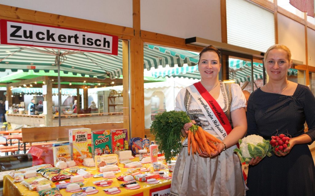 Der informative „Zuckertisch“ bewies beim Hoffest seine große Anziehungskraft und verblüffte die Betrachter mit den Zuckermengen, die vielfach gut „versteckt“ sind. Gesundheitsdezernentin und Erste Kreisbeigeordnete Diana Stolz wies mit Spargelkönigin Stefanie II. auf gesundheitsbewusste Ernährung hin. Foto: Hannelore Nowacki